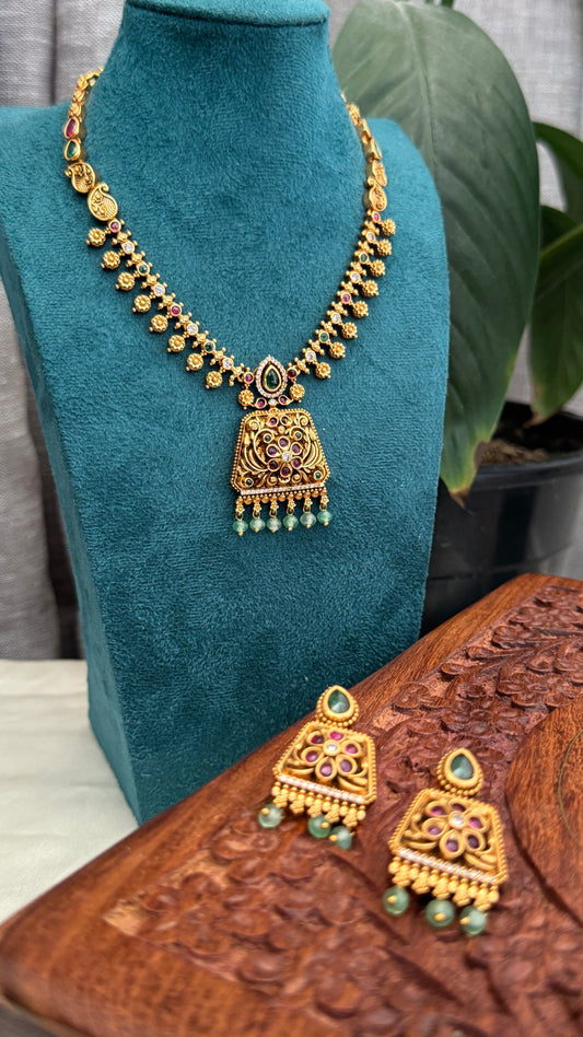 Necklace set with emerald, ruby and white color stone details.