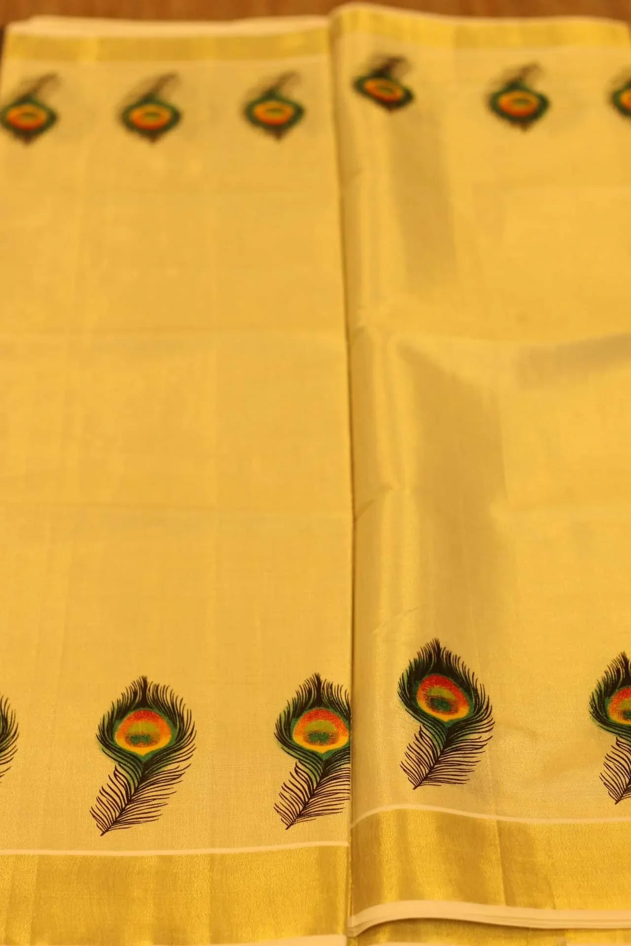 Onam saree with gold border and peacock feather design