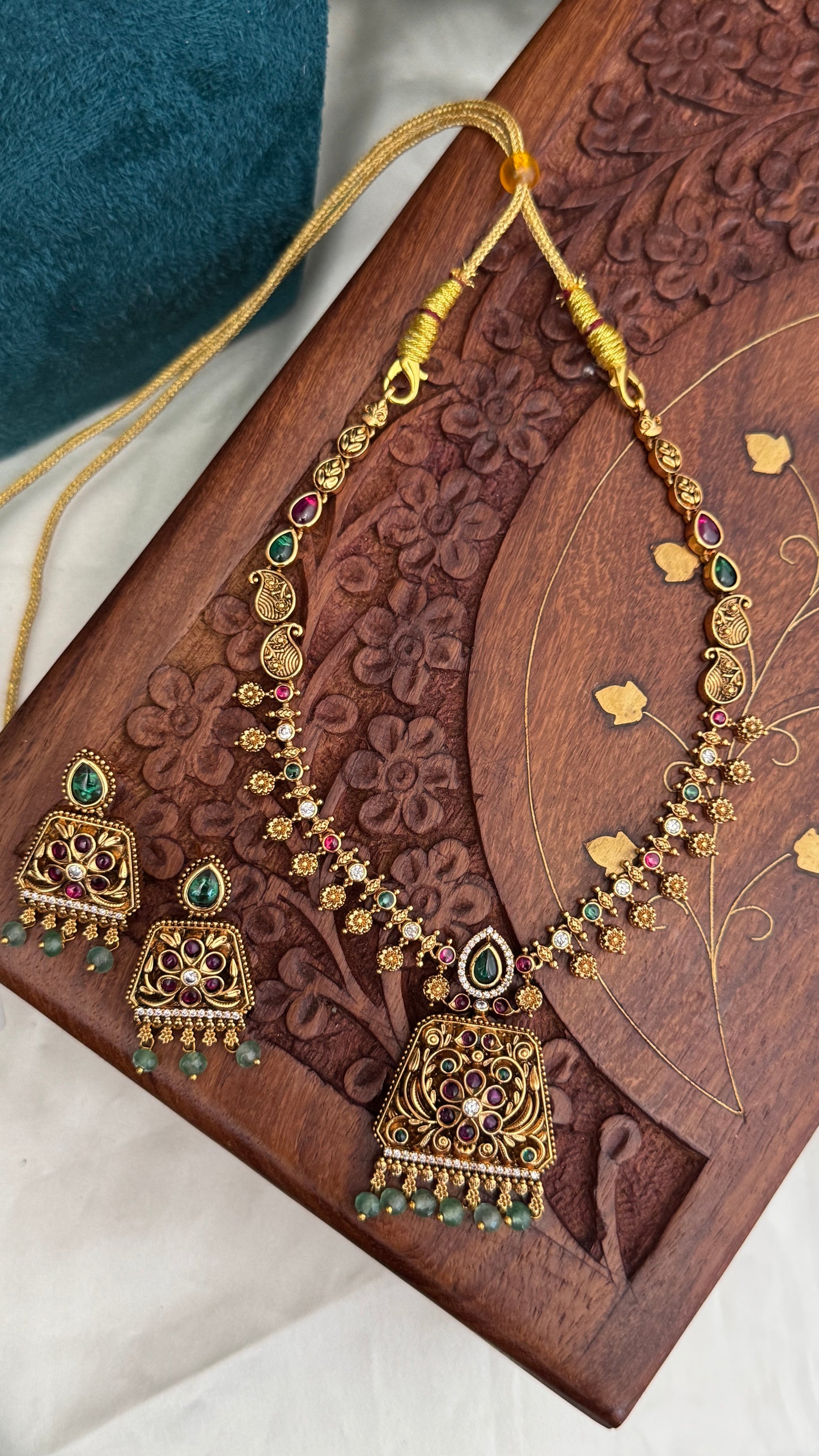 Necklace set with emerald, ruby and white color stone details.