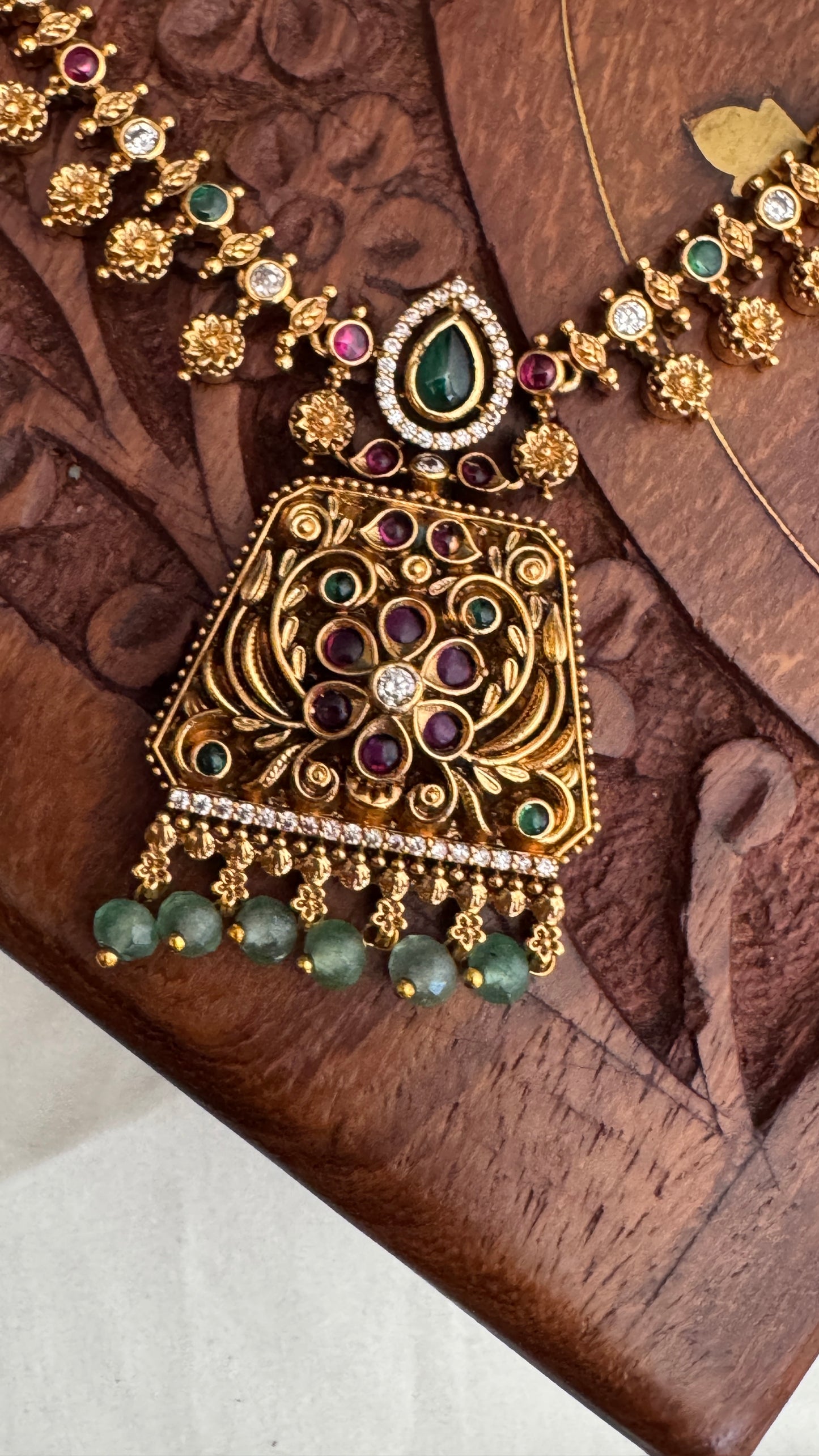 Necklace set with emerald, ruby and white color stone details.